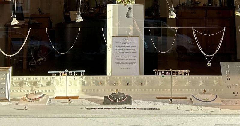 Auslage im Schaufenster: Ketten, Anhänger, Ohrringe an kleinen Ständern und Schmuck auf Büsten