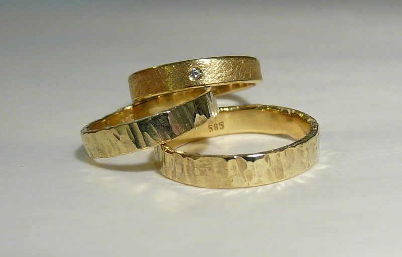 Drei goldene Ringe: zwei mit gehämmerter Oberfläche, einer fein mattiert mit einem kleinen eingesetzten Stein